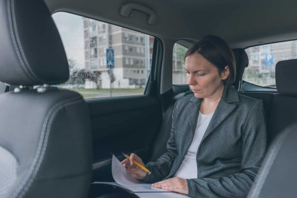 businesswoman-doing-business-paperwork-on-car-back-seat